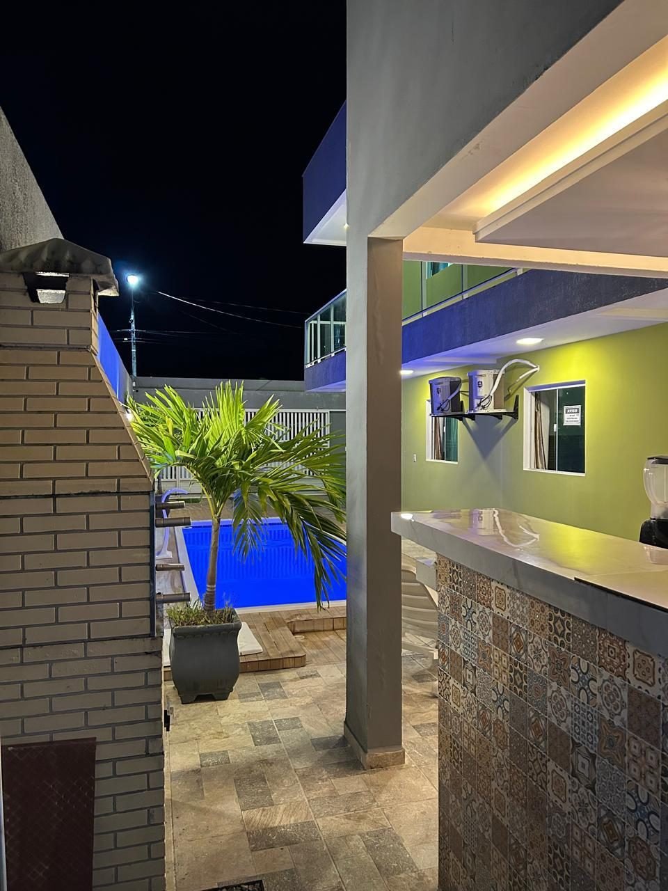 Área de bar e churrasqueira à noite, ao lado da piscina
