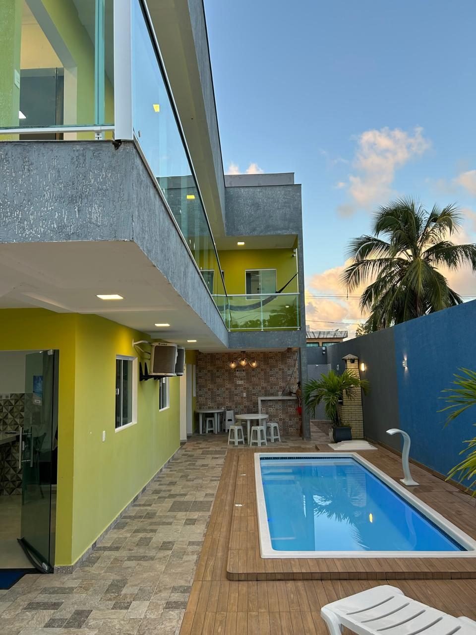 Piscina do WT Corais Flats no fim da tarde, com deck de madeira e coqueiro